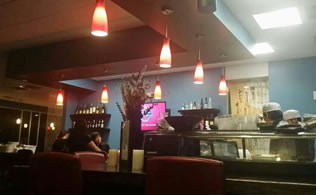 Kumo Sushi bar with chefs preparing food under red pendant lights