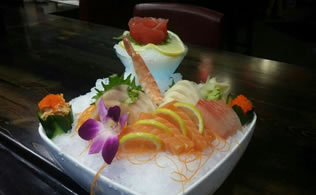 Assorted sashimi and sushi platter on ice with orchid garnish